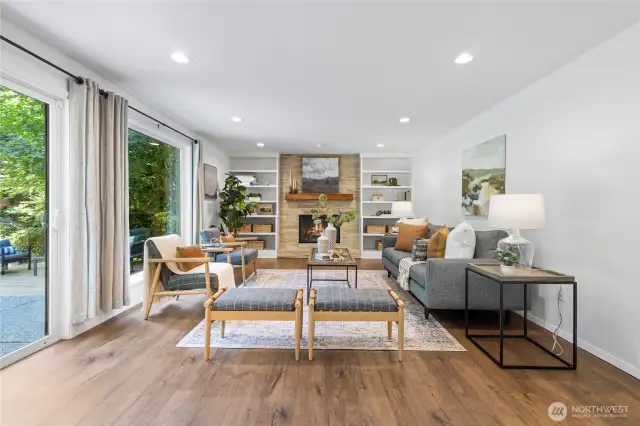 The inviting family room features a cozy gas fireplace and stunning floor-to-ceiling views of the lush backyard.