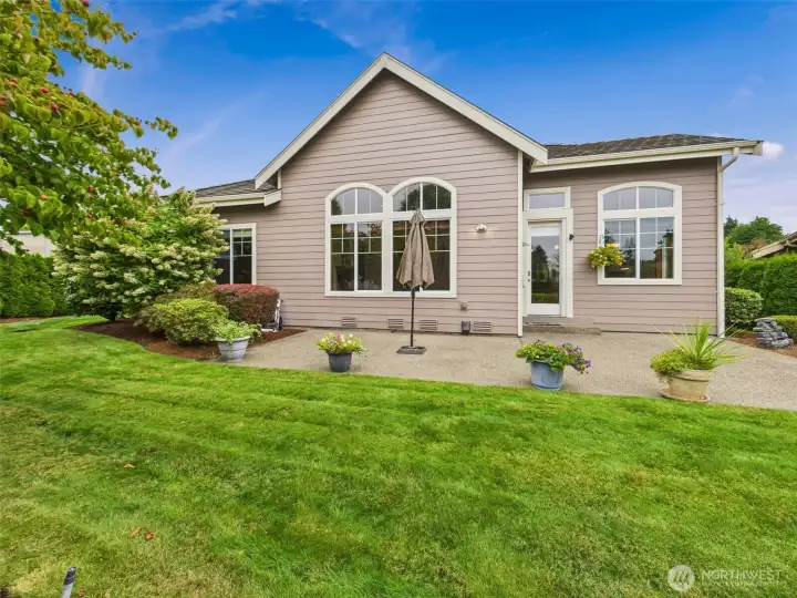 Beautifully landscaped backyard patio area with fruit trees, raised garden beds and roses.