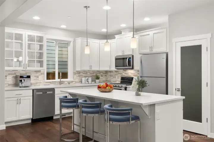 Gorgeous kitchen with walk-in pantry featuring quartz counters, designer lighting and backsplash.