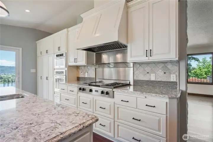 Gourmet kitchen offers abundant custom cabinetry, quartz countertops, & high end SS appliances, and more river views.