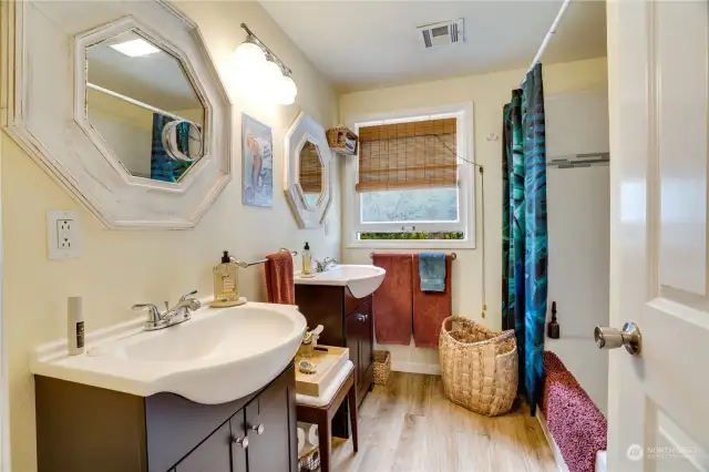 The guest bathroom sits between the two bedrooms, Separate vanities and tub/shower.