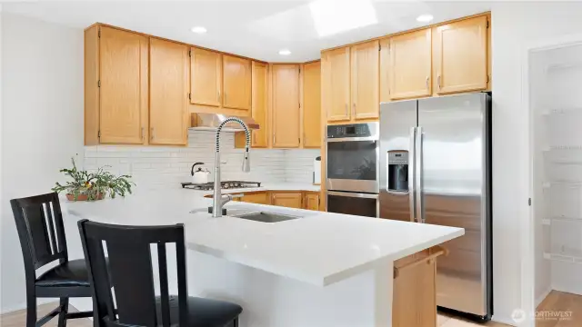 The skylights bring in the natural light which complements the natural wood of the cabinet and hardwood flooring.  The breakfast counter area is perfect for eating, meeting, homework, everything that is not set up for a formal dining room meal. It's perfect for every meal that you eat outside of the dining room.  The walk-in pantry is to the right.