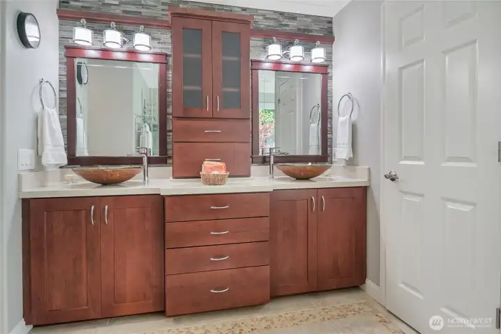 Custom cabinetry, solid surface counters and designer vessel sinks add to the lavish feeling in the primary bath.