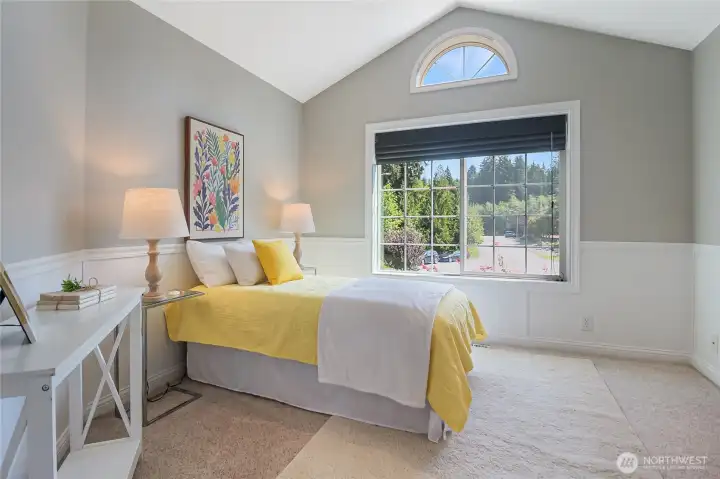 One of the secondary bedrooms offers a vaulted ceiling and half-round window. Wainscotting adds that stylish feeling to this room. The closet offers a closet organizer.