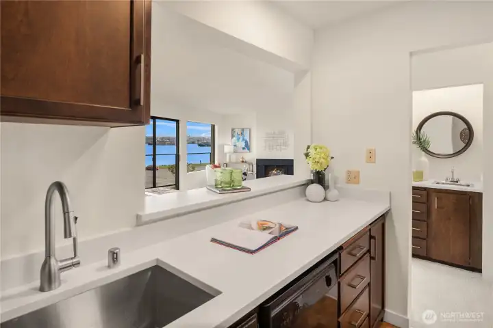 A new extra deep sink and faucet grace this spotless kitchen. A wet bar is seen across the hall to the right.