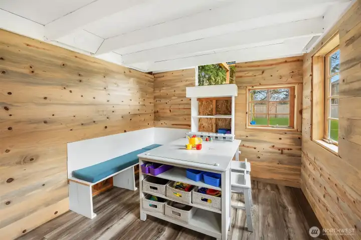Inside the custom-built playhouse, cozy bench seating with cushions and a built-in art table create the perfect spot for play, crafts, or quiet imagination. Battery-operated lighting and a solar charging panel add functionality.