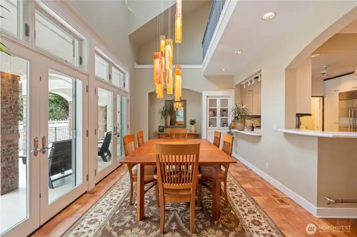 Beautiful dining room with a 2 story ceiling, skylight, a double set of French doors, lots of natural light which will only enhance the stunning chandelier.