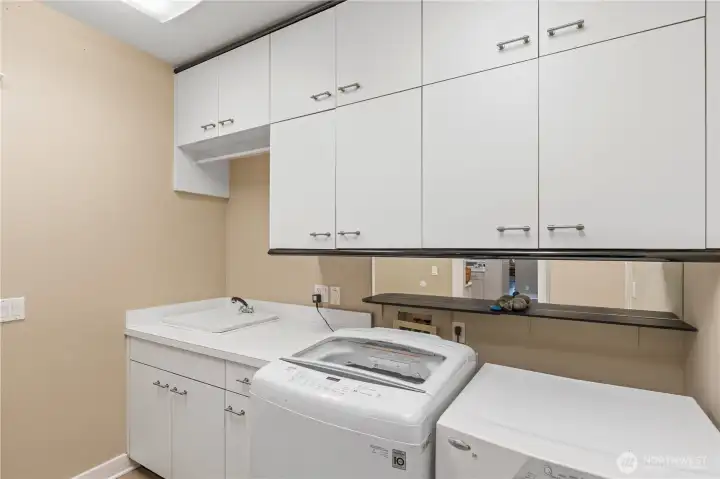 Spacious laundry room with utility sink & lots of cabinets.