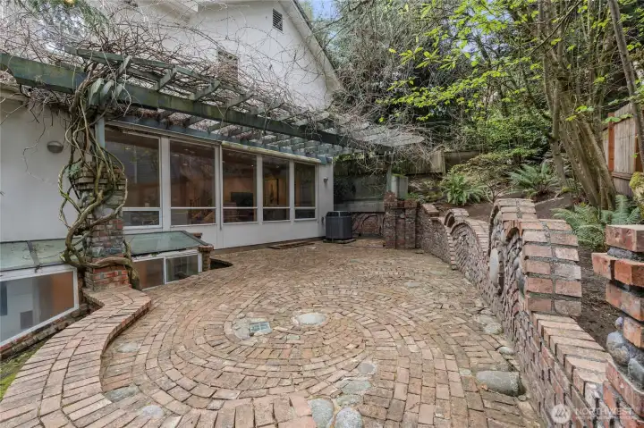Beautiful custom brickwork patio with gorgeous wisteria plant over trellis.