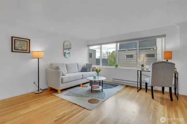 Spacious living room features a large West-facing window and gleaming refinished hardwood floors.