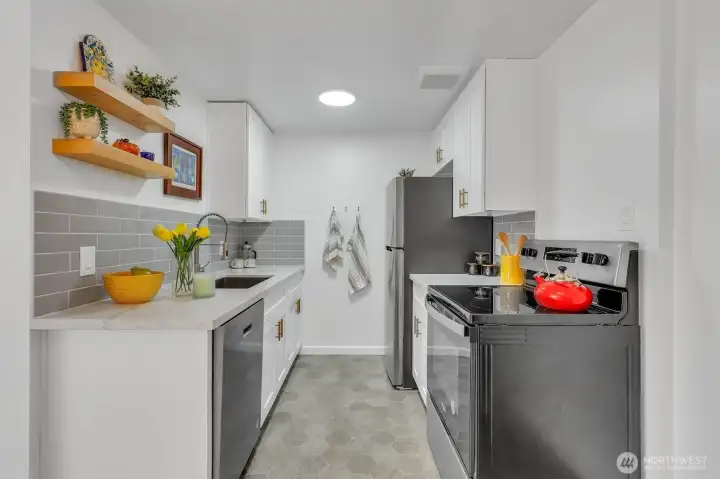 The kitchen has been tastefully updated with new cabinetry, quartz countertops, stainless appliances, and cool tile backsplash.