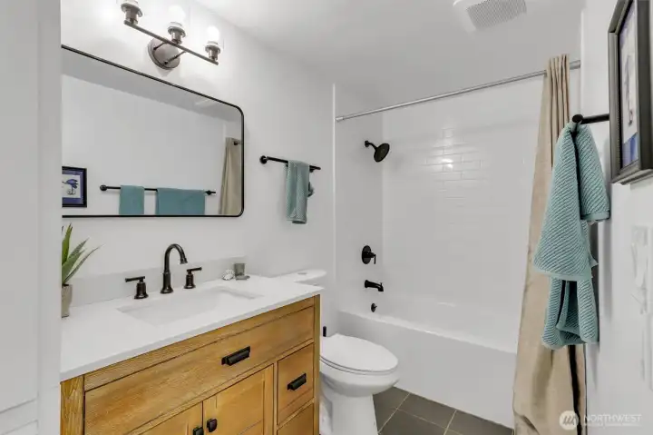 The bathroom has also been completely updated with large beautiful vanity, new tub, toilet, tile floor, tile tub surround, cool mirror, and fixtures. To the left of this photo (not shown) is a large linen closet.