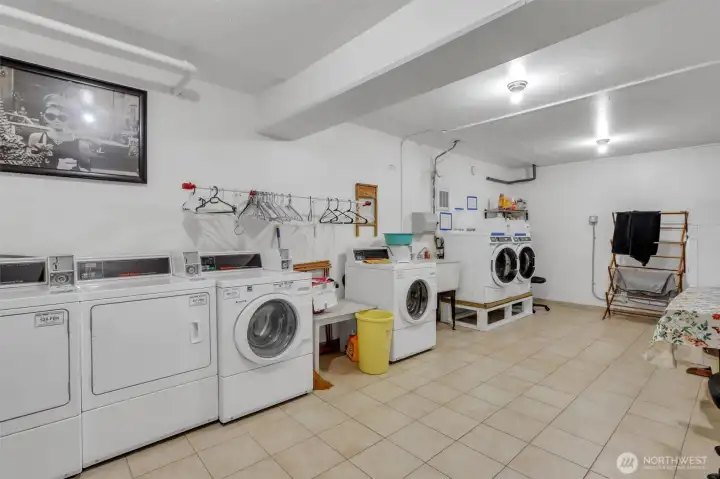 Spacious and bright, the convenient laundry room features a sink, folding table, drying racks and 3 sets of washers and dryers.