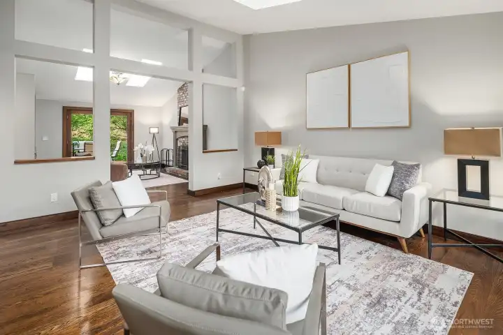 Another angle of the bright and airy living space highlights the open sightlines, vaulted ceilings, and wide plank hardwood floors that flow seamlessly through the main level.