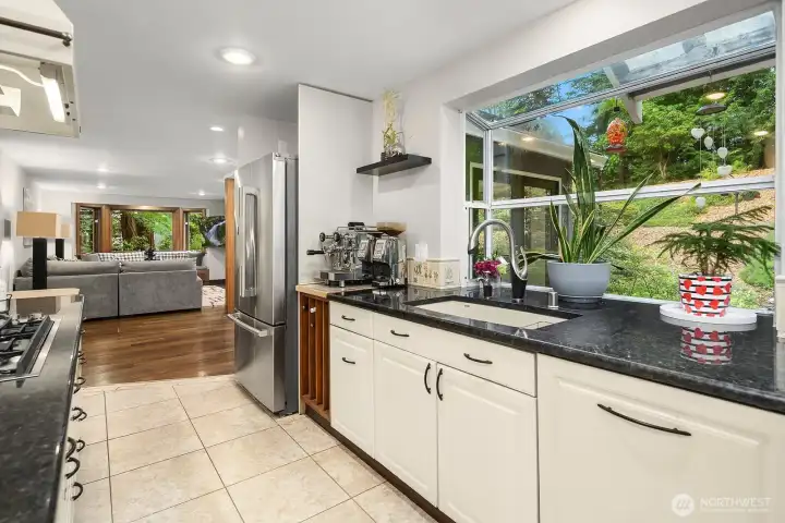 The kitchen's generous counter space, classic white cabinetry, and large windows overlooking the lush landscape make this a bright and highly functional space for everyday cooking and entertaining.