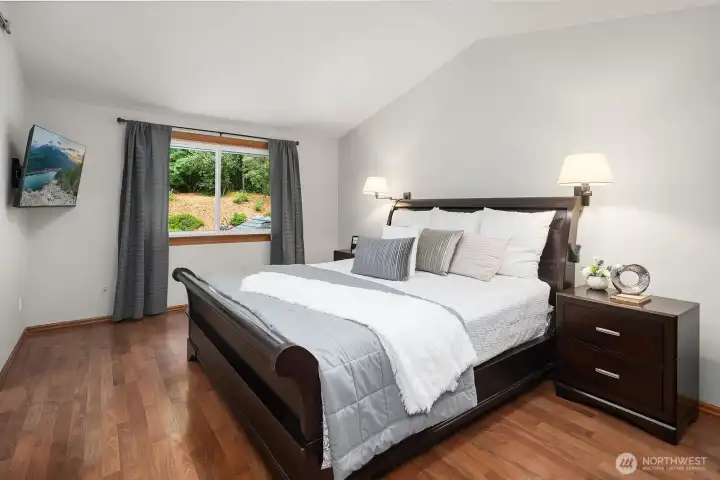 The spacious primary suite offers a serene retreat with rich hardwood floors, warm natural light, and generous proportions that set the stage for the luxurious ensuite bath beyond.