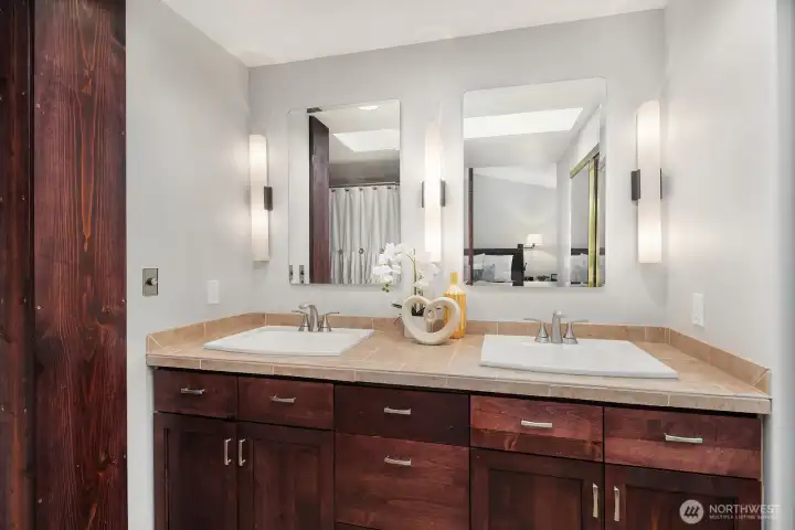 The primary ensuite features dual vanities with rich wood cabinetry and elegant fixtures, offering a refined and functional space to start and end each day.