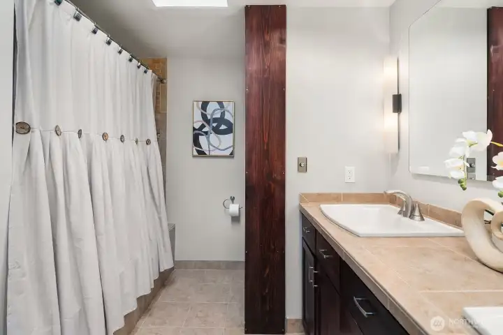 The primary bath continues with a skylight-lit shower area and warm wood accents, completing the luxurious 5-piece ensuite experience.