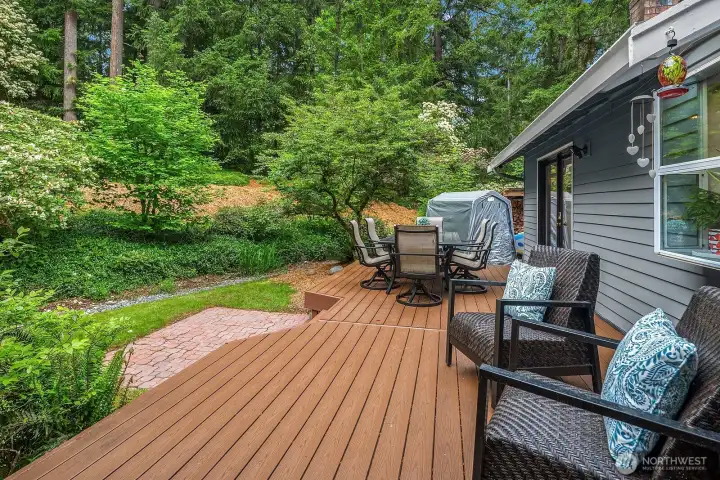 The expansive deck offers a beautiful outdoor living space surrounded by mature trees and lush landscaping, creating a private and serene setting perfect for entertaining or simply unwinding in nature.
