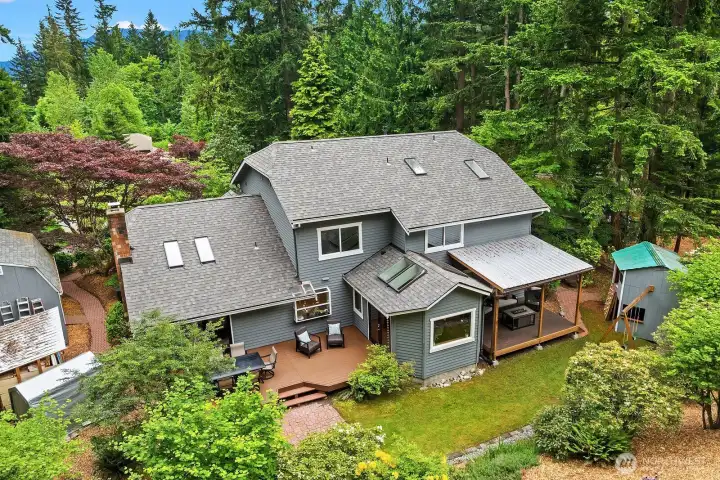 This overhead view highlights the expansive deck, lush terraced landscaping, and the home's generous footprint nestled privately among the mature trees of this coveted Pine Lake cul-de-sac lot.