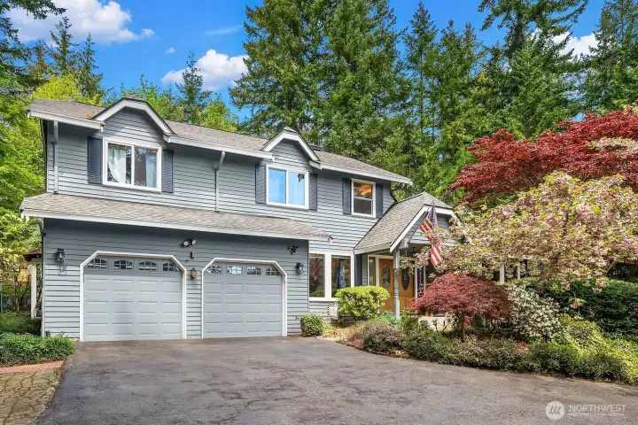 The inviting craftsman exterior showcases beautiful curb appeal with a two-car garage, vibrant flowering landscaping, and a warm and welcoming facade perfectly framed by the mature trees of this exceptional Pine Lake cul-de-sac setting.
