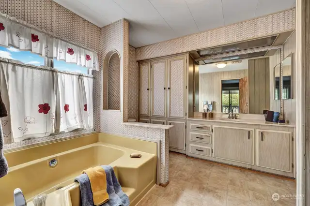 Primary bath has soaking tub, step in shower, make desk, single vanity and ample storage for all your bathing and personal items.