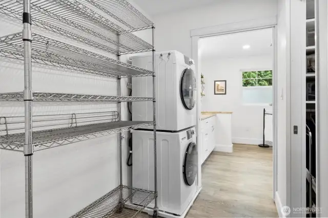 hallway to primary bath has laundry on left and walk-in closet on right