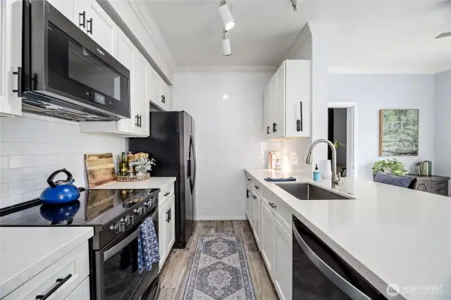 Quartz counters      Beautiful white cabinets with soft close drawers    White subway tile backsplash     White tile accent wall    Black Whirlpool stainless refrigerator     Black Whirlpool smart oven and microwave     Black dishwasher with stainless accents    Undermount sink with wand / track lighting