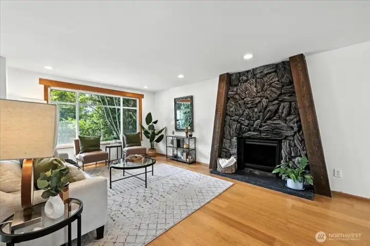 Large windows and wood burning fireplace in living room.