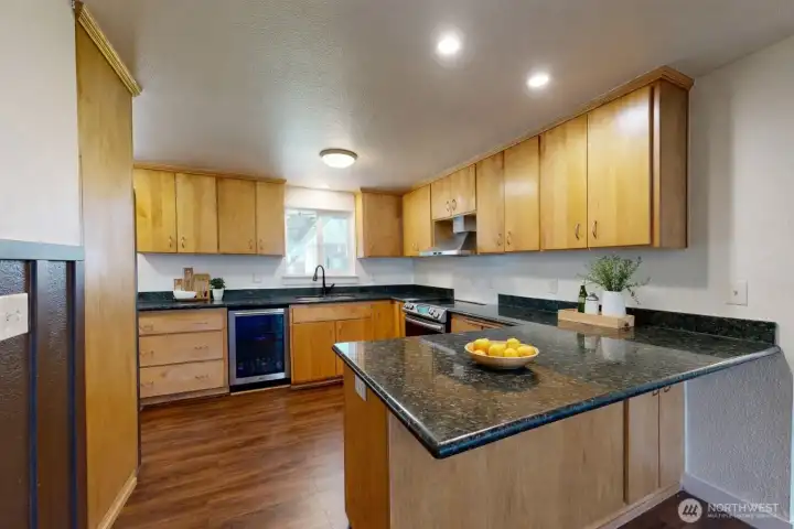 Kitchen featuring wood cabinetry, countertops, and breakfast bar. The photo is virtually staged.