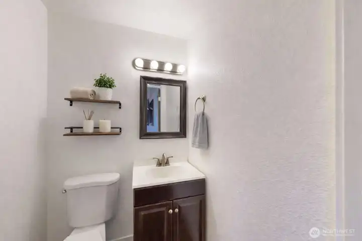Powder room featuring a white vanity with integrated sink, brushed nickel fixtures, and modern vanity lighting. The photo is virtually staged.