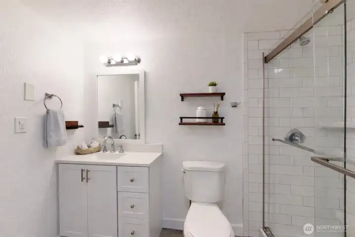 Master bath featuring walk-in shower enclosed with clear glass and finished with classic white subway tile. The photo is virtually staged.