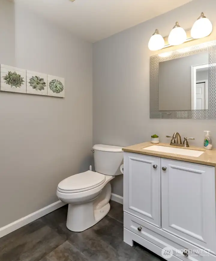 Convenient half bathroom with updated vanity, modern lighting, and clean, low-maintenance flooring.