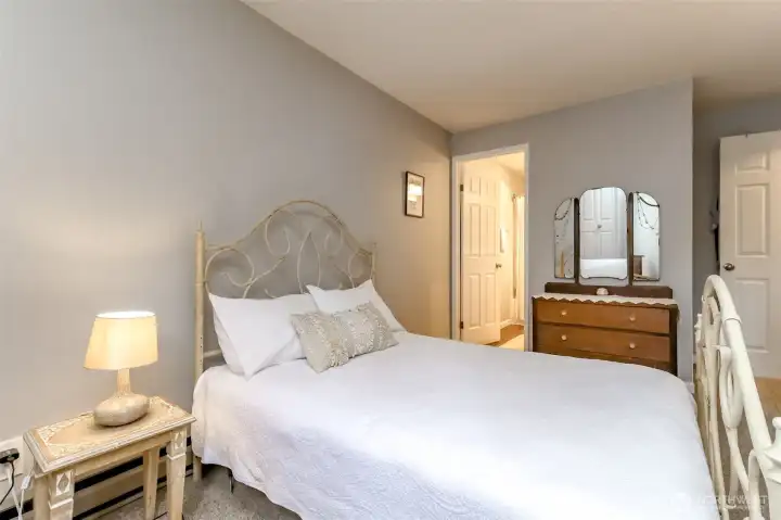 “Bright primary bedroom with soft natural light, neutral tones, and space for a queen or king bed.