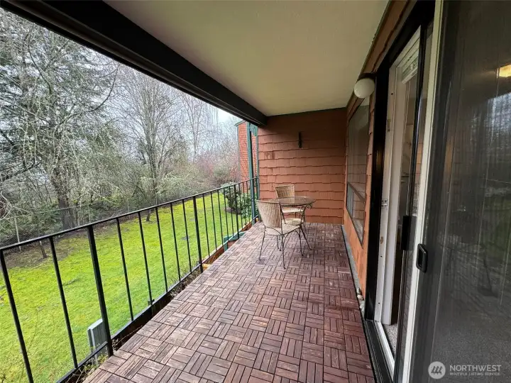 Balcony overlooking a green belt with roller shade.