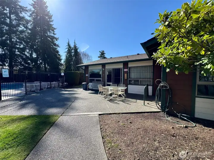 Clubhouse patio overlook the pool, with a bike rack and exterior hose.