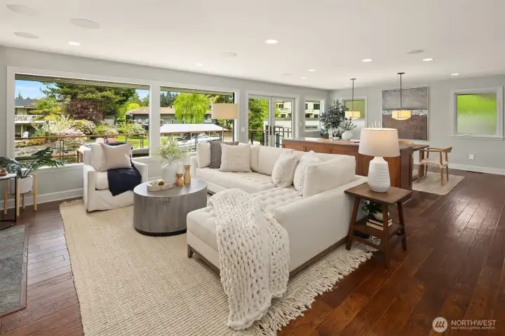 Morning light fills the space, coffee in hand, doors open to the deck—an easy, natural flow from kitchen to living to water that defines daily life here.