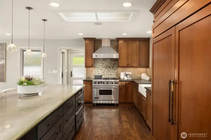 Designed to gather, the oversized island—finished in slate shaker cabinetry—offers generous prep space, casual seating, and effortless connection. A Sub-Zero refrigerator, GE Profile dishwasher, and Sharp microwave drawer bring quiet performance behind the scenes.