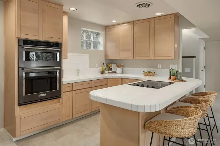 A fully equipped secondary kitchen with maple cabinetry, a Maytag cooktop, KitchenAid oven and microwave, and under-counter refrigeration—designed for effortless hosting or independent living.