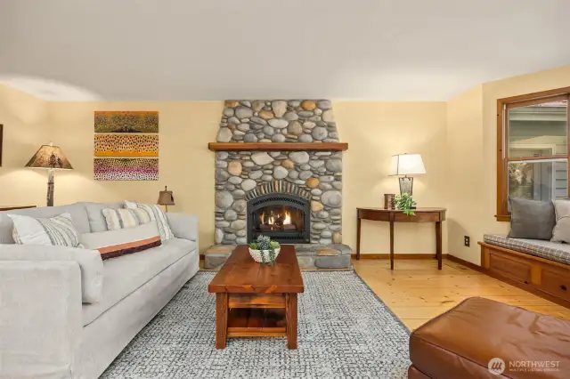 The welcoming living room has a river rock fire place (propane) and beautiful wide plank wood floors.