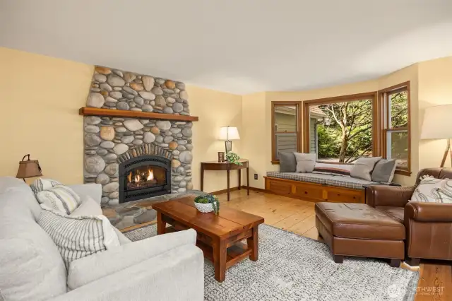 The living room includes a cozy window seat looking out on the mature evergreen trees.
