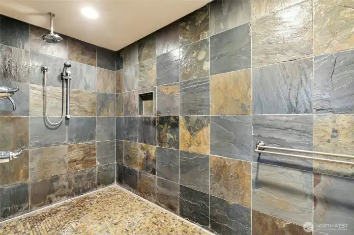 Elegant spa-style primary bath showcasing a 7-function body spray system and impressive custom stone craftsmanship.