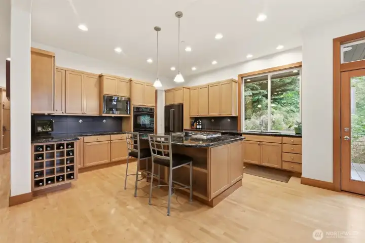 Natural wood tones pair perfectly with the green landscape surrounding the home. This kitchen offers a gas cooktop, granite countertops and abundant cabinet space. Natural wood tones pair perfectly with the green landscape surrounding the home. This kitchen offers a gas cooktop, granite countertops and abundant cabinet space.