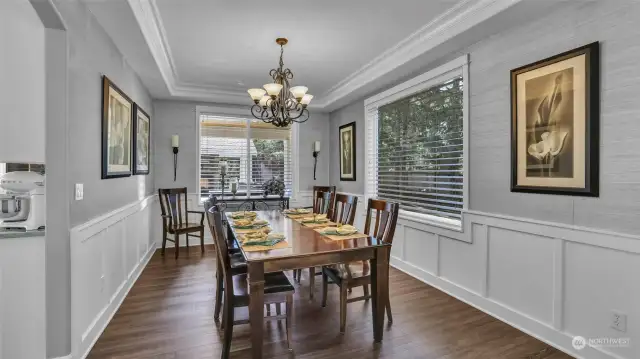 Wainscoting, tray ceiling, and stylish light fixtures add to the elegance of this formal dining room just off the kitchen.