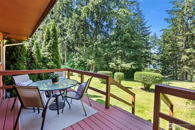 The deck opens onto the expansive lawn and has a partial view of Henderson Bay.