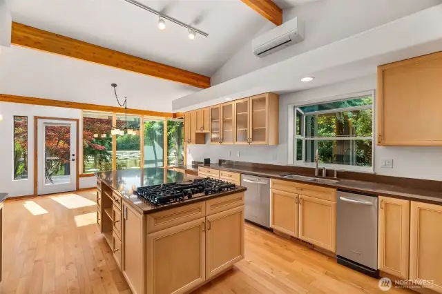 The kitchen has been fully remodeled with granite counters, custom cabinetry, island with gas cooktop, and double oven. Notice the ductless heat pump here that supplements the forced air furnace and provides ample cooling.