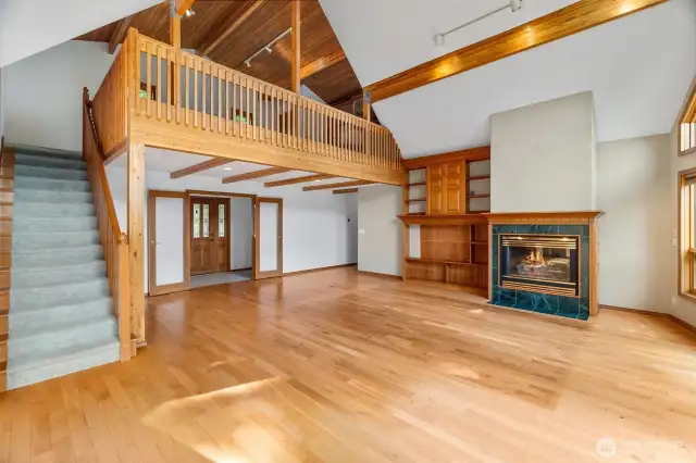 The great room with loft above, propane fireplace, entry with french doors and custom wall cabinets.