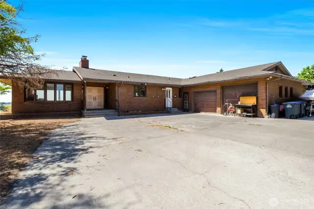 This brick home has five bedrooms and three bathrooms. There are three front entrances, one double door, and two single doors, as well as two garage doors, one a couple of feet taller than the other. This is the main garage.