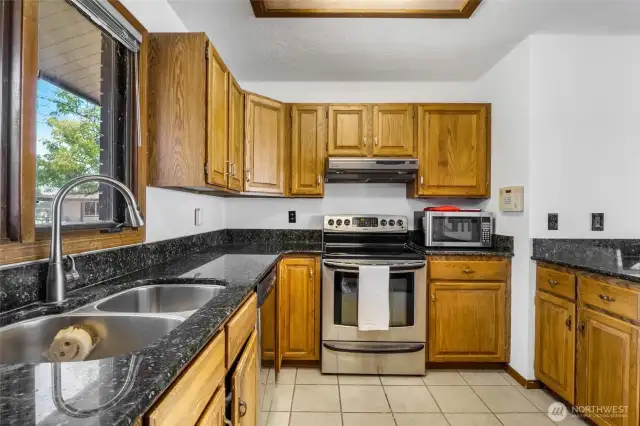 The tile flooring and granite countertops are easy to maintain, and you'll love the stainless steel appliances in here. At the sink, enjoy observing the neighborhood from your window. The kitchen sink scrubby is even smiling at the thought of you living here!