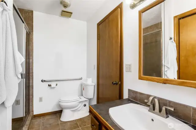 Included in the primary bath is a tiled shower, tile flooring, and as needed, a grab bar by the commode. The elongated sink has a faucet with a type of brushed nickel feature with handles on both sides of the spout. And of course, a mirror cabinet is handy for hiding all your toiletries when they're not in use.